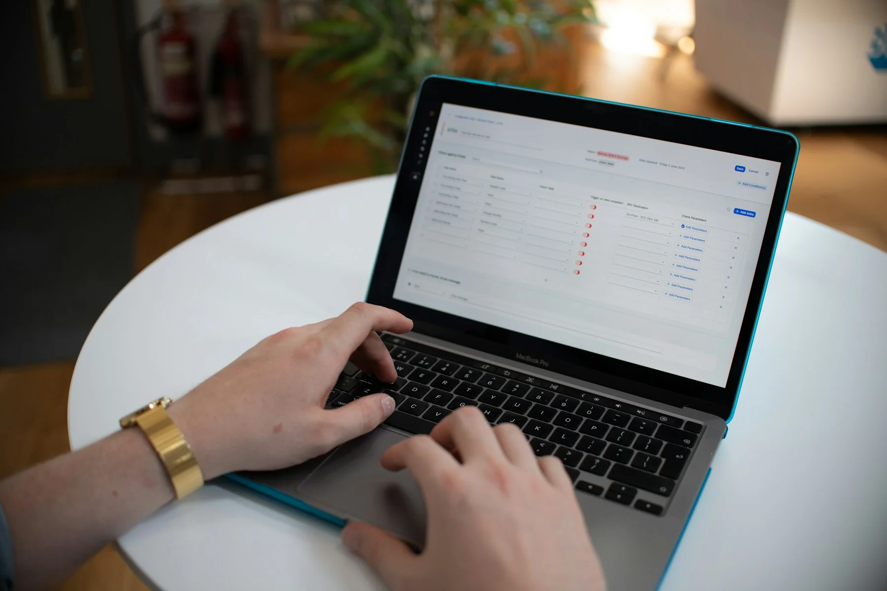 Hands typing on a laptop displaying a workflow automation and rule-configuration dashboard