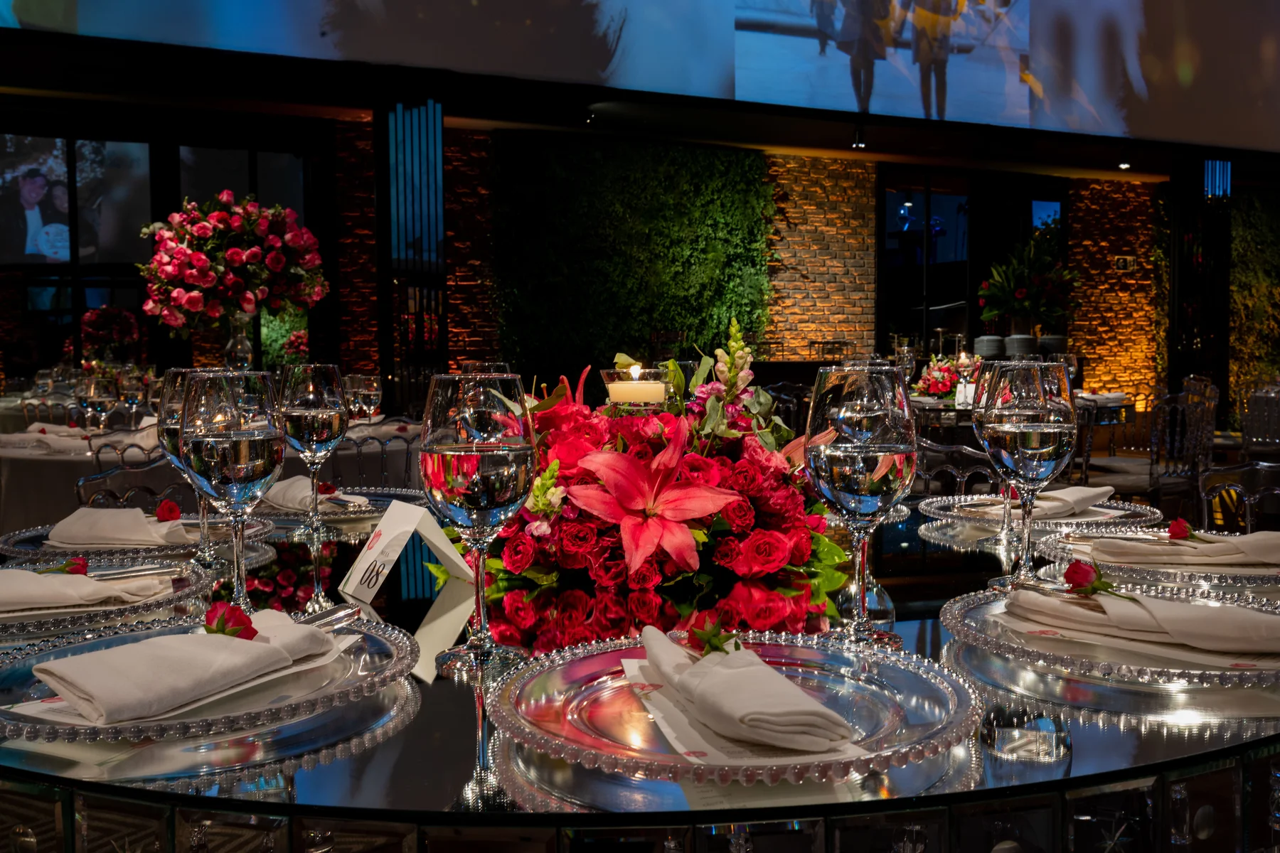 Elegant gala dinner table setting with red floral centerpieces, candlelight, and silver charger plates Elegant gala dinner table setting with red floral centerpieces, candlelight, and silver charger plates