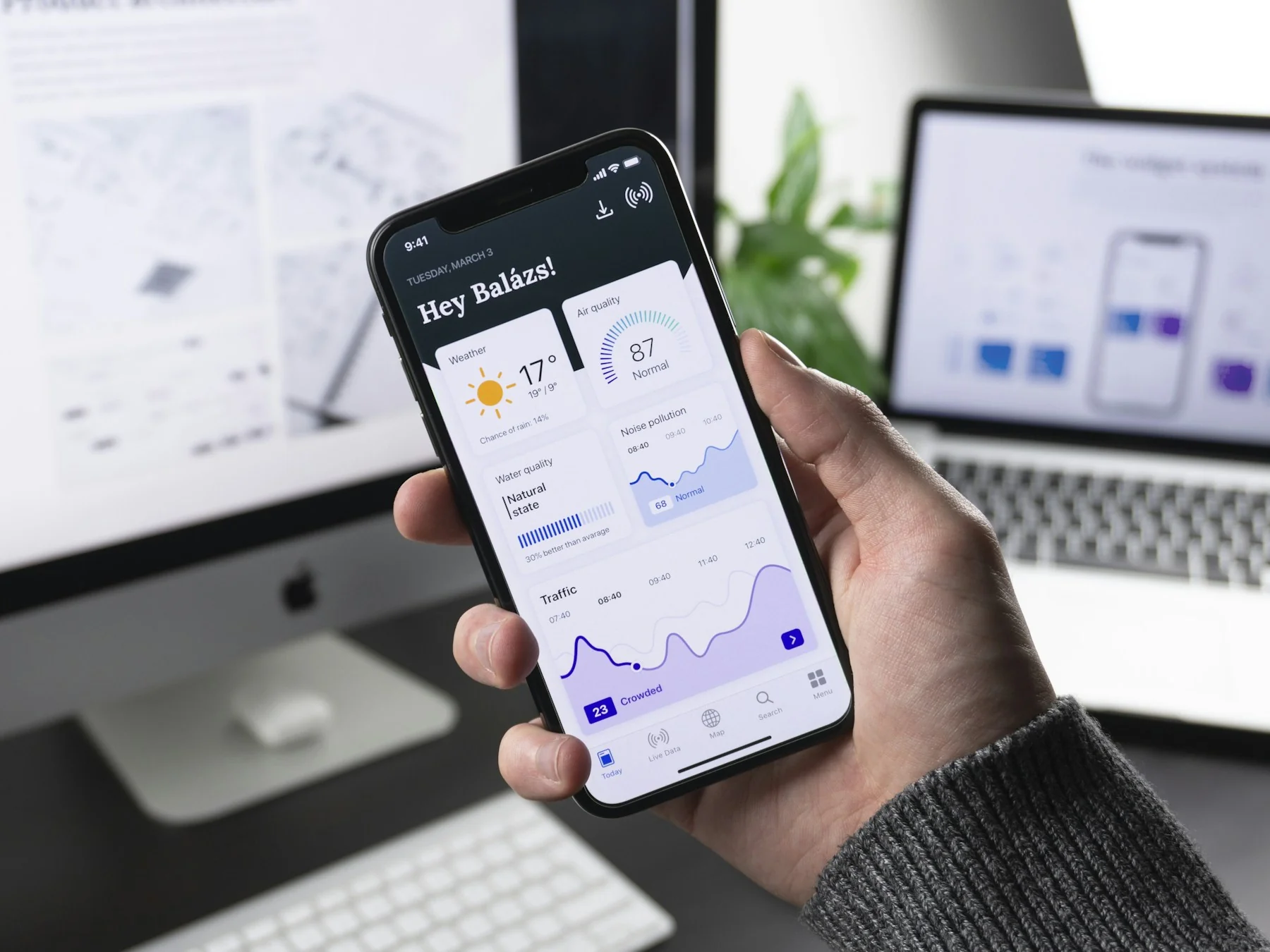 Hand holding a phone showing a custom mobile app dashboard