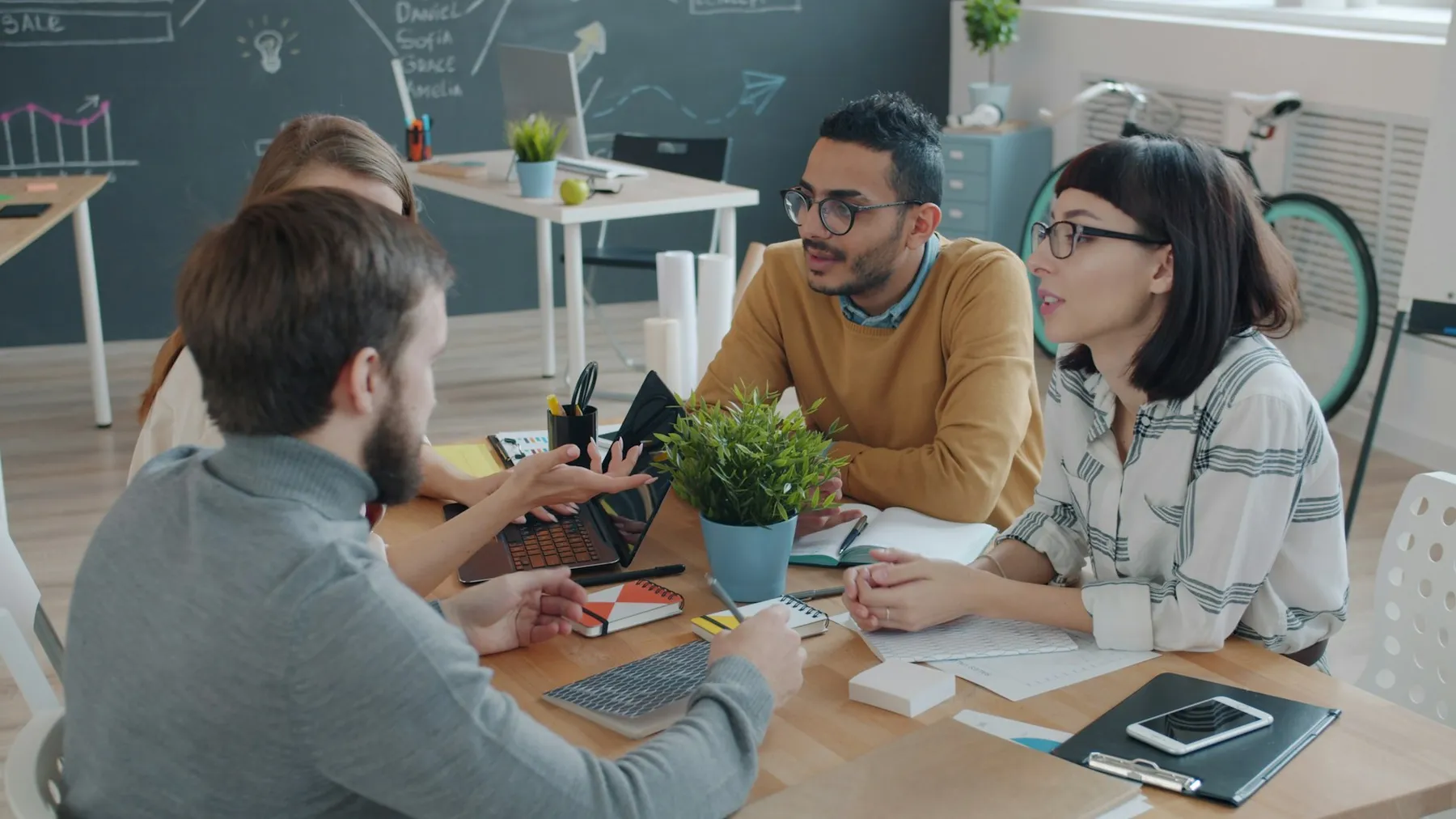 Diverse team of colleagues in a candid discussion around a laptop in a modern office